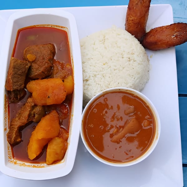 Ponce Restaurant's Puerto Rican meal with stewed beef, rice, beans, and fried plantains.